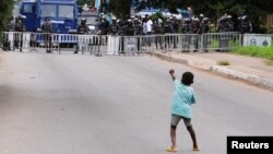 A young boy gestures at police as demonstrators gather in the streets for a third day of anti-government protests in Accra, Ghana, Sept. 23, 2023.