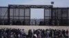 Un grupo de migrantes aguarda en Ciudad Juárez, México, junto al muro fronterizo con la esperanza de poder entrar en Estados Unidos el 30 de marzo de 2023.