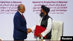Mullah Abdul Ghani Baradar, leader of the Taliban delegation, and Zalmay Khalilzad, U.S. envoy for peace in Afghanistan, shake hands after signing an agreement in Doha, Qatar, Feb. 29, 2020.