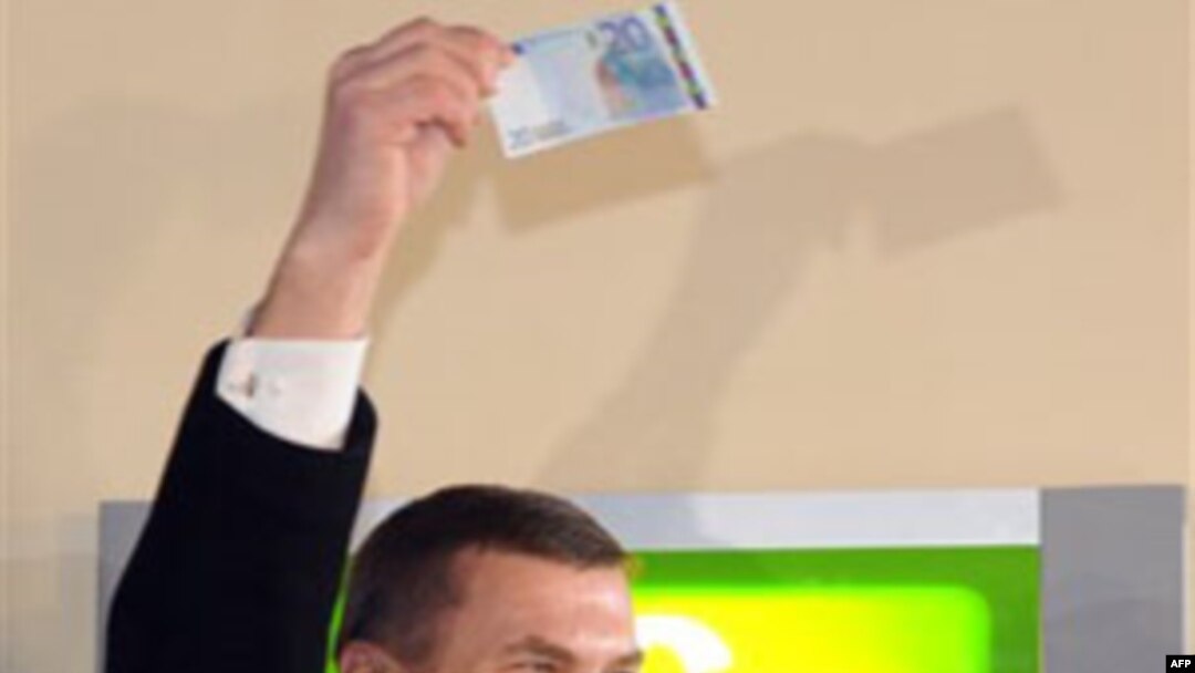 Thủ tướng Estonia Andrus Ansip giơ cao tờ 20 euro vừa rút khỏi máy rút tiền