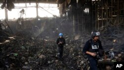 Wartawan berjalan di dalam gudang yang hancur untuk menyimpan makanan, setelah serangan dari Rusia di Brovary, di pinggiran Kyiv, Ukraina, 29 Maret 2022. (Foto: AP)