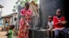 Judith Andeka, veuve et mère de cinq enfants, va chercher de l'eau avec un seau dans le bidonville de Kibera, à Nairobi, au Kenya, le 10 avril 2020. (AP Photo/Brian Inganga)
