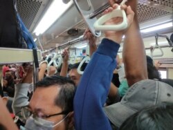 Para penumpang, sebagian besar mengenakan masker, tampak berdesakan di dalam kereta di Jakarta, hari Senin (23/3) di tengah perebakan virus corona. (Foto: Reuters)