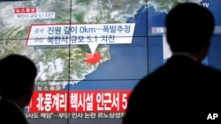 People walk by a screen showing the news reporting about an earthquake near North Korea's nuclear facility, in Seoul, South Korea, Wednesday, Jan. 6, 2016.