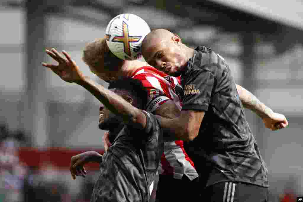 Brentford's Mathias Jensen, center, goes for the header with Arsenal's Thomas Partey, left, and his teammate Gabriel during the English Premier League soccer match between Brentford and Arsenal, at the Gtech Community stadium, London.