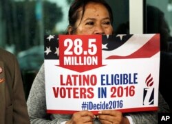 FILE - Georgina Arcienegas holds a sign in support of Latino voters during a protest outside the office of Florida Rep. Carlos Trujillo, Jan. 12, 2016, in Doral, Florida.