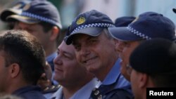 El presidente de Brasil, Jair Bolsonaro, posa con oficiales de policía en la favela Estrutural, en Brasilia, el 27 de abril de 2019.