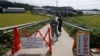 Quarantine officials wear protective gear as a precaution against African swine fever at a pig farm in Paju, South Korea, Sept. 17, 2019. The notice reads: "Under quarantine."