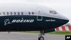  A pilot waves from the flight deck of a Boeing 737 MAX 9 as it rolls out for the airplane's first flight, April 13, 2017, in Renton, Washington.