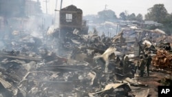 Sisa-sisa kios pedagang masih mengepulkan asap setelah api membakar sebuah pasar di Nairobi, Kenya. 28 Juni 2018 (foto: AP Photo/Khalil Senosi).