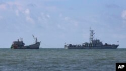 FILE - A Myanmar navy vessel tows a boat with migrants, off the country's Thameehla island, May 31, 2015.