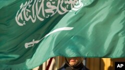 FILE - An honor guard member is covered by the flag of Saudi Arabia, in Washington, March 22, 2018. In the past 24 hours the kingdom reportedly carried out a record number of executions.