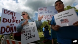 FILE - Protesters holds signs as they stand with others outside an event where Republican presidential candidate, Donald Trump and New Jersey Gov. Chris Christie were to appear on May 19, 2016 in Lawrenceville, N.J. 