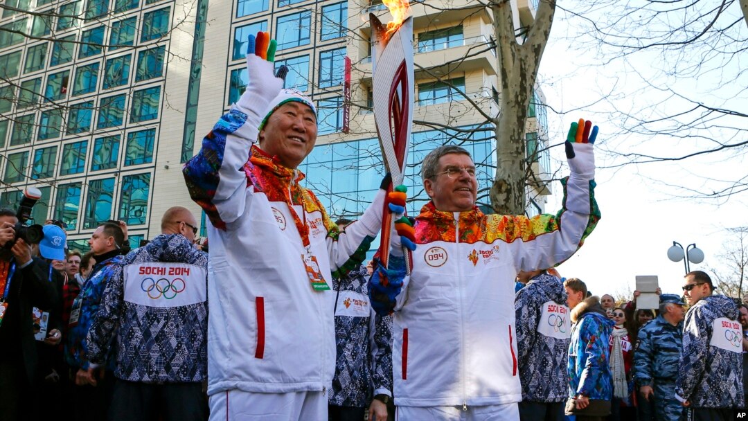 Chủ tịch Ủy ban Olympic Quốc tế Thomas Bach (phải) chuyền ngọn đuốc cho Tổng thư ký LHQ Ban Ki-moon bên dòng sông Sochi, 6/2/14