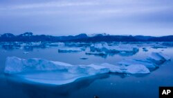 FILE - A boat navigates next to large icebergs near the town of Kulusuk, in eastern Greenland, Aug. 15, 2019. 