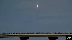 Los espectadores observan desde un puente en Titusville, Florida, mientras el SpaceX Falcon 9 despega con dos astronautas a bordo el 30 de mayo de 2020.