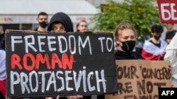Orang-orang Belarus yang tinggal di Polandia menunjukkan poster yang bertuliskan "Kemerdekaan bagi Roman Protasevich" dalam unjuk rasa menuntut pembebasan narablog itu di depan kantor Komisi Eropa di Warsawa, Senin, 24 Mei 2021. (Foto: Wojtek Radwanski/AFP)