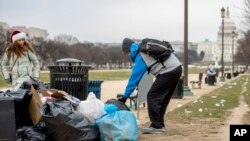 The Capitol building is visible as a man who declined to give his name picks up garbage and stacks it near a trash can during a partial government shutdown on the National Mall in Washington, Dec. 25, 2018. 