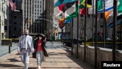 A couple wearing protective masks is seen as the outbreak of the coronavirus disease (COVID-19) continues in the Manhattan borough of New York City, New York, U.S., April 12, 2020. REUTERS/Jeenah Moon