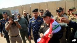 Perdana Menteri Irak Haider al-Abadi (tengah) memegang bendera nasional Irak saat tiba di Mosul, Irak, 9 Juli, 2017. (Foto:dok) 