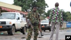 FILE - A Burundian soldier with his gun and rocket launcher guard a deserted street in Bujumbura, Burundi.