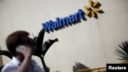 A man talks on his mobile phone in front of a Wal-Mart store in Sao Paulo, Brazil, Feb. 16, 2016.