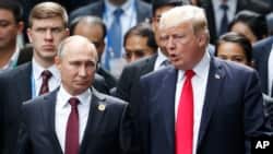 Le président russe Vladimir Poutine, à gauche, et le président américain Donald Trump discutent lors de la séance de photos de famille en marge du sommet de la Coopération économique Asie-Pacifique (APEC) à Danang, Vietnam, 11 novembre 2017.