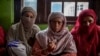 Mother and two relatives of Kashmiri student Arshid Yusuf who was arrested in Uttar Pradesh for sharing congratulatory WhatsApp messages in support of Pakistani cricket team.The mother is showing a photo of the arrested son. (VOA/Faisal Bashir)