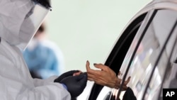 A woman's blood is collected for testing of coronavirus antibodies at a drive-through testing site in Hempstead, N.Y., April 14, 2020. 