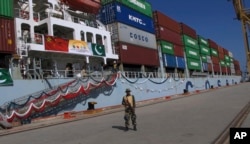 FILE - A Pakistani soldier stands guard while a loaded Chinese ship prepares to depart Gwadar port, about 700 kilometers (435 miles) west of Karachi. Pakistan, Nov. 13, 2016.