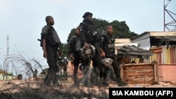 Des policiers ivoiriens marchent à côté de pneus brûlés après des manifestations, le 14 août 2020, à Daoukro, dans l'est de la Côte d'Ivoire. - Cinq personnes ont été tuées et plus de 100 blessées au cours des 3 jours d'affrontements. (Photo by SIA KAMBOU / AFP)