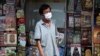 Un homme portant un masque facial pour aider à freiner la propagation du nouveau coronavirus se tient devant une librairie à Bangkok, en Thaïlande, le mardi 26 mai 2020. (AP Photo/Sakchai Lalit)
