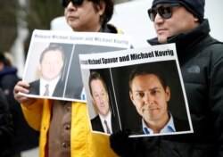 FILE - People hold signs calling for China to release Canadian detainees Michael Spavor and Michael Kovrig during an extradition hearing for Huawei Technologies Chief Financial Officer Meng Wanzhou in Vancouver, Canada.