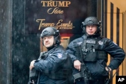 FILE - Heavily armed police officers stand guard in the rain outside Trump Tower in New York, Nov. 29, 2016.