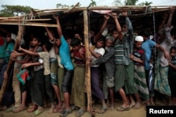 FILE - Rohingya refugees jostle as they line up for a blanket distribution under heavy rainfall at the Balukhali camp near Cox's Bazar, Bangladesh, Dec. 11, 2017.