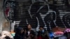 ARCHIVO - Migrantes venezolanos esperan ayuda frente a la Comisión Mexicana de Ayuda a Refugiados en la Ciudad de México, en octubre de 2019.