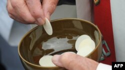 FILE - A priests holds communion wafers after a mass at La Prairie in Lourdes, Sept. 14, 2008.