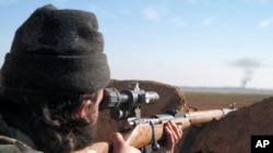 A militant fighter aims a sniper rifle during fighting in Tal Tamr, Hassakeh province, Syria, in this image posted by the Al-Baraka division of the Islamic State group, Feb. 24, 2015.