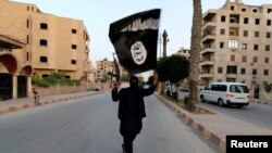 Anggota yang setia kepada ISIL melambaikan bendera ISIL di Raqqa, 29 Juni 2014.