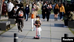 2020年4月3日戴著口罩的女孩在南韓首爾公園騎踏板車。