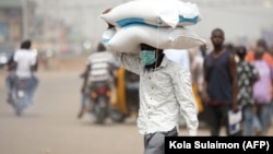 Un homme porte des sacs de riz sur la tête à une frontière entre Abuja et l'État de Nasarawa le 30 mars 2020.