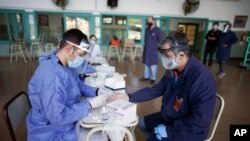 Un trabajador de la salud le hace una prueba de COVID-19 a un maestro en la escuela Hipólito Yrigoyen, en Buenos Aires.