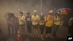 Members of the 'Wall of Moms' protest group lock arms as they are tear-gassed by federal officers during a Black Lives Matter protest at the Mark O. Hatfield United States Courthouse, July 27, 2020, in Portland, Ore.