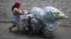 Seorang perempuan berjalan di sepanjang 41st Street dengan tas berisi botol dan kaleng untuk didaur ulang di wilayah Manhattan di New York, 30 September 2015. (REUTERS / Carlo Allegri)