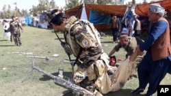 FILE - A wounded man is tended to following multiple explosions in Lashkar Gah, Afghanistan, March 23, 2019. 