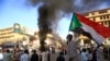 Seorang pria Sudan membawa bendera negaranya dalam aksi protes di ibu kota Sudan, Khartoum, pada 19 Desember 2020, untuk menunjukkan rasa frustrasi akan tidak adanya perubahan yang berarti sejak militer berkuasa pada 2019 lalu. (Foto: AFP/Ashraf Shazly)