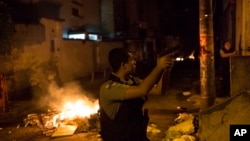 Pasukan anti huru-hara Brazil berpatroli dekat barikade yang dibakar massa dalam bentrokan di daerah kumuh Pavao Pavaozinho di Rio de Janeiro (22/4).